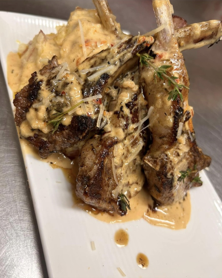 StuffedEnuff lamb chops topped with creamy sauce on a white plate